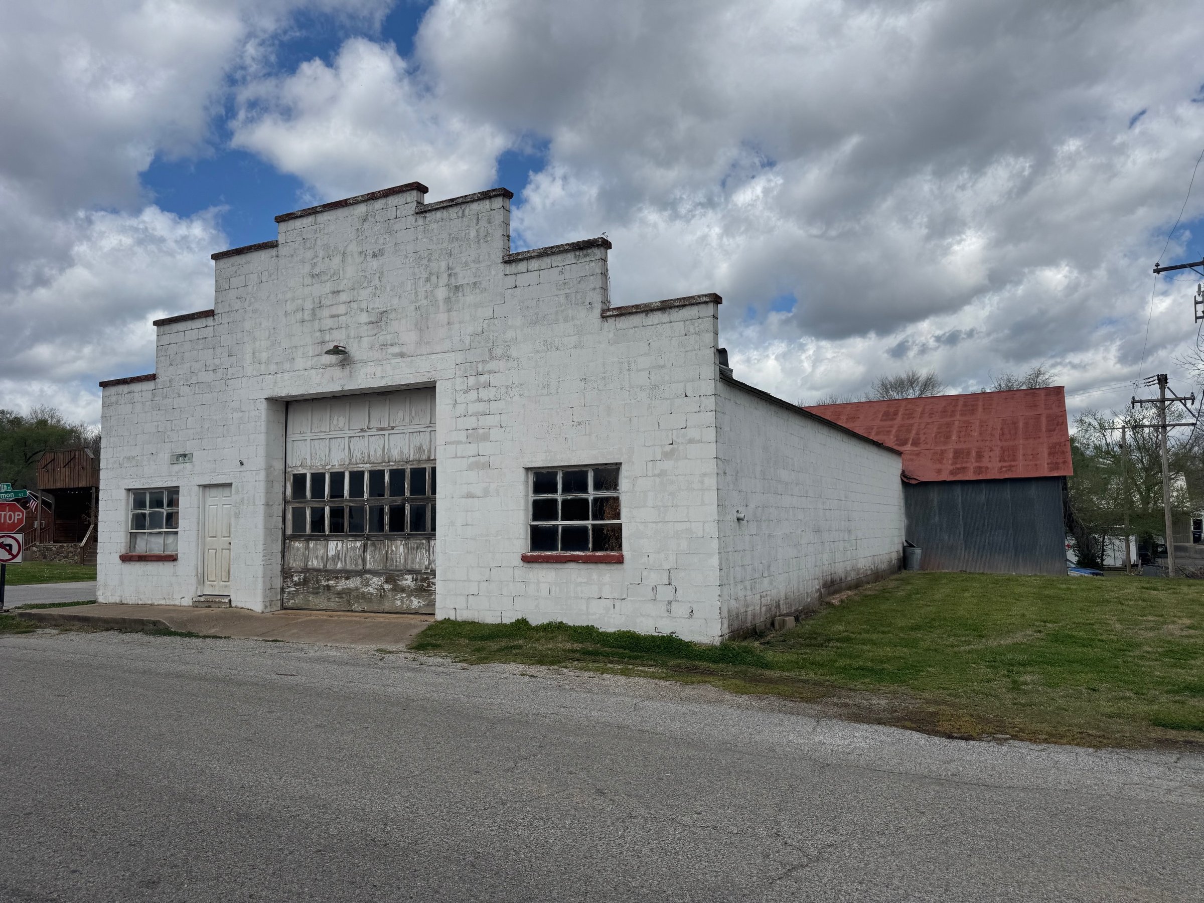The front of the Riverbend Hollow building today: a white block facade with a stepped roofline, old garage door and two windows